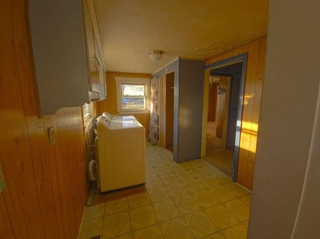 clothes washing area with washer and dryer, light floors, and wooden walls