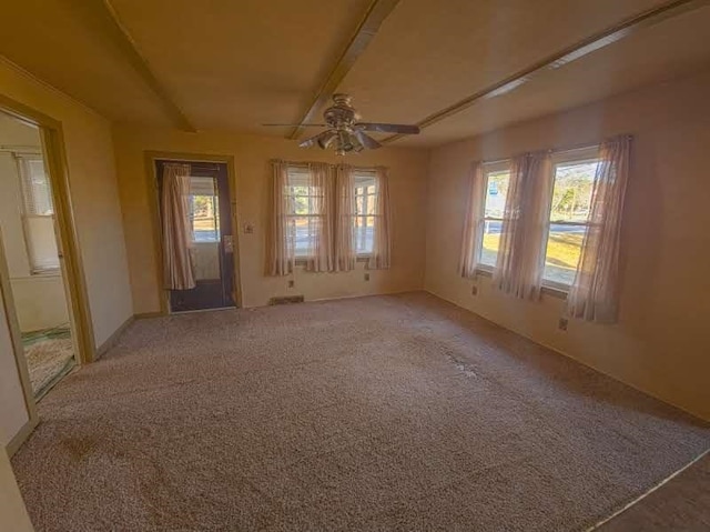 unfurnished room featuring beam ceiling, light colored carpet, and a ceiling fan