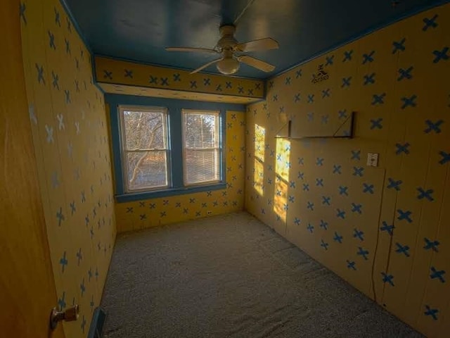 carpeted empty room with wallpapered walls and a ceiling fan