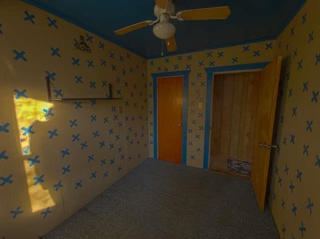 spare room featuring wallpapered walls, carpet, and a ceiling fan