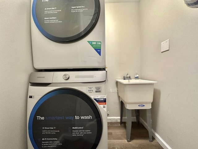 clothes washing area featuring hardwood / wood-style flooring and stacked washer / dryer