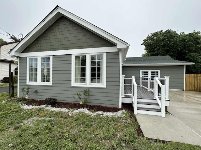 rear view of house with a wooden deck, a yard, and a patio