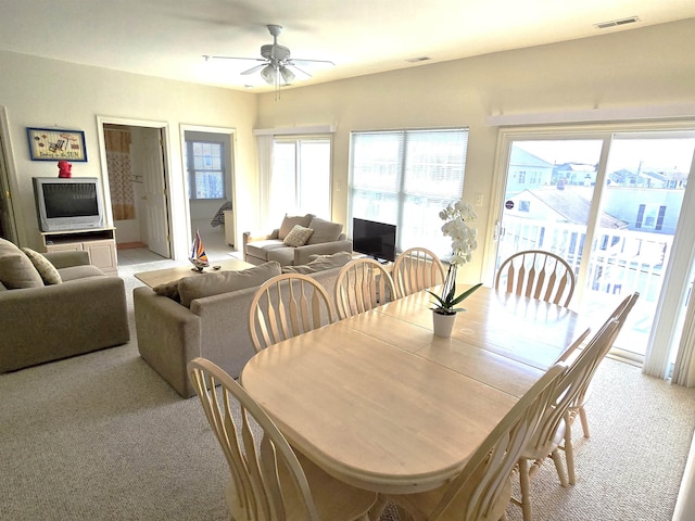 dining area featuring ceiling fan and light colored carpet