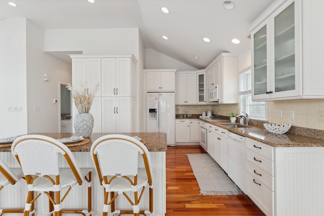 kitchen featuring decorative backsplash, white appliances, white cabinets, and dark stone counters