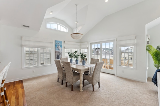 dining room featuring high vaulted ceiling and light colored carpet