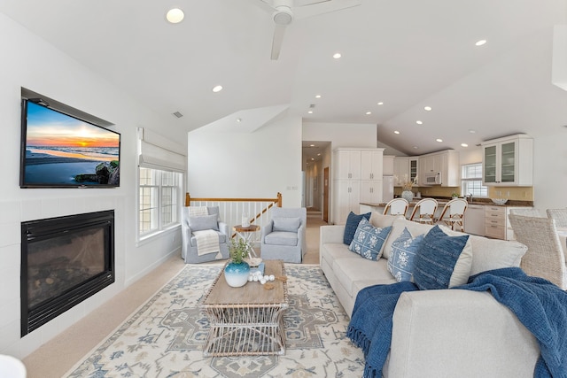 living room with a fireplace, ceiling fan, and lofted ceiling