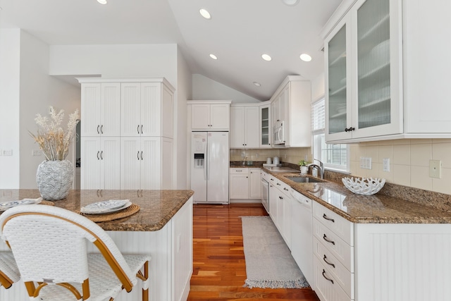 kitchen with sink, white cabinets, hardwood / wood-style floors, white appliances, and dark stone countertops