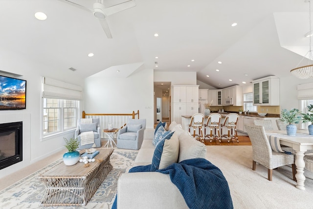 carpeted living room with a fireplace, vaulted ceiling, and ceiling fan