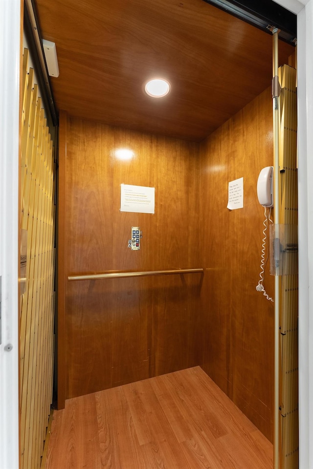 room details with wood ceiling, elevator, and wood walls