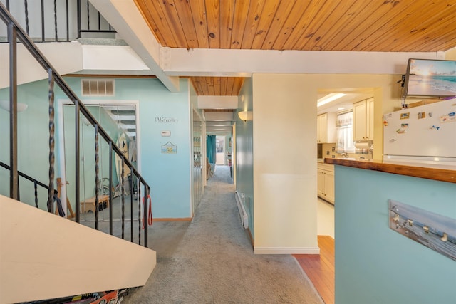 hall featuring wood ceiling, light carpet, and beamed ceiling