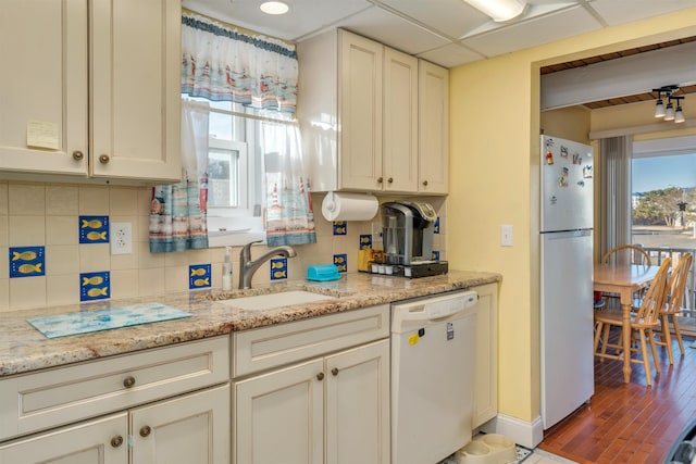 kitchen featuring white dishwasher, sink, stainless steel fridge, and a healthy amount of sunlight