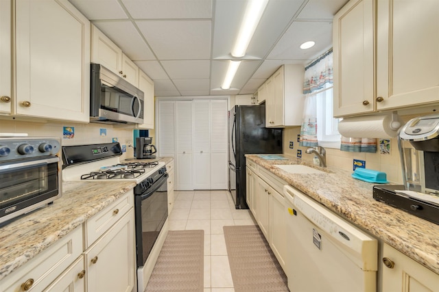 kitchen with white appliances, light stone countertops, sink, and light tile patterned floors