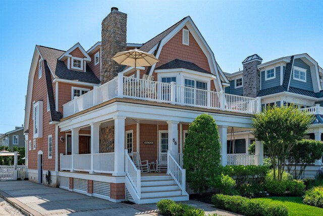 56 E 22nd St, Avalon, NJ 08202 - view of front of home with covered porch, a chimney, a balcony, a gambrel roof, and roof with shingles