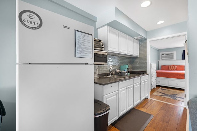 8401 Atlantic Ave # 405, Wildwood Crest, NJ 08260 - kitchen with freestanding refrigerator, white cabinetry, stainless steel microwave, backsplash, and light wood-type flooring