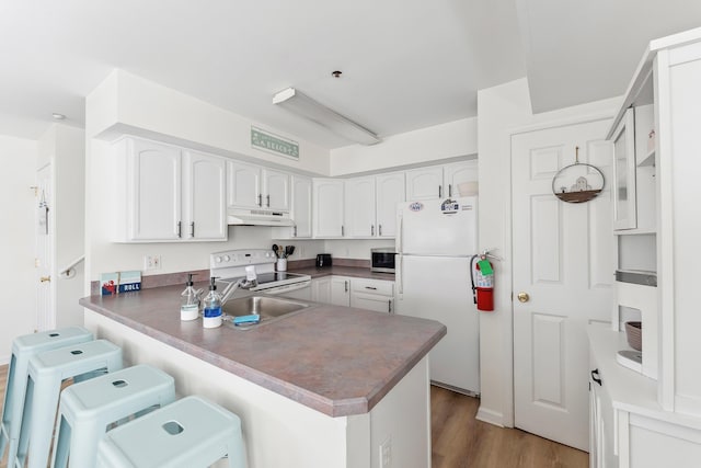 316 E 17th Ave Unit 6, North Wildwood, NJ 08260 - kitchen with white appliances, under cabinet range hood, a peninsula, a breakfast bar, and white cabinets