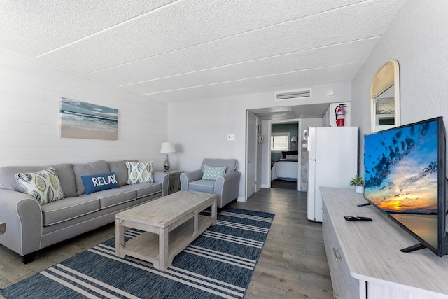 living area featuring wood finished floors, a textured ceiling, and wooden walls