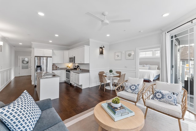 living room with crown molding, ceiling fan, sink, and dark wood-type flooring