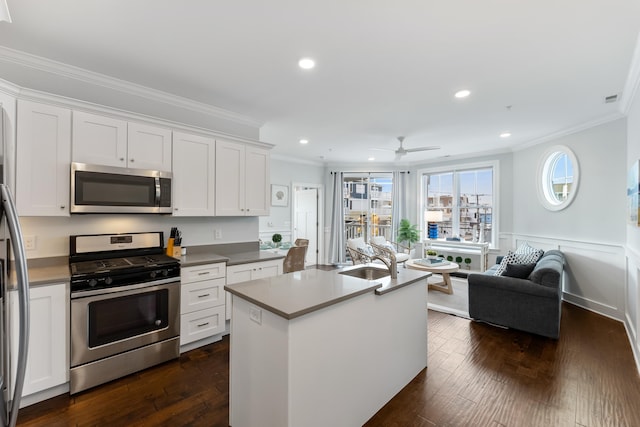 kitchen featuring a kitchen island with sink, white cabinets, ceiling fan, ornamental molding, and appliances with stainless steel finishes