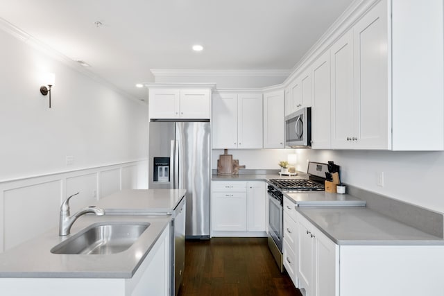 kitchen with ornamental molding, stainless steel appliances, dark wood-type flooring, sink, and white cabinets