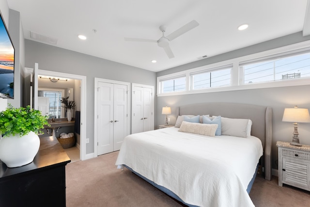 bedroom with ceiling fan, dark carpet, and two closets