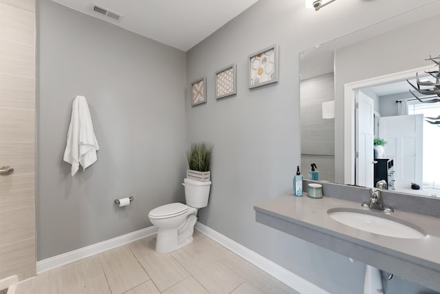 bathroom with tiled shower, toilet, sink, and a chandelier