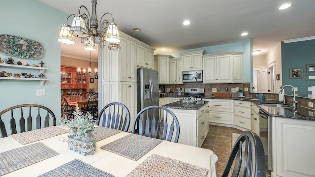 kitchen with an inviting chandelier, stainless steel appliances, tasteful backsplash, pendant lighting, and sink