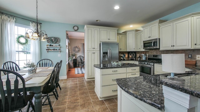 kitchen featuring decorative light fixtures, tasteful backsplash, tile patterned flooring, appliances with stainless steel finishes, and cream cabinets