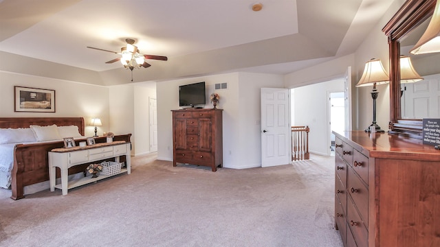 bedroom featuring ceiling fan, light colored carpet, and a tray ceiling