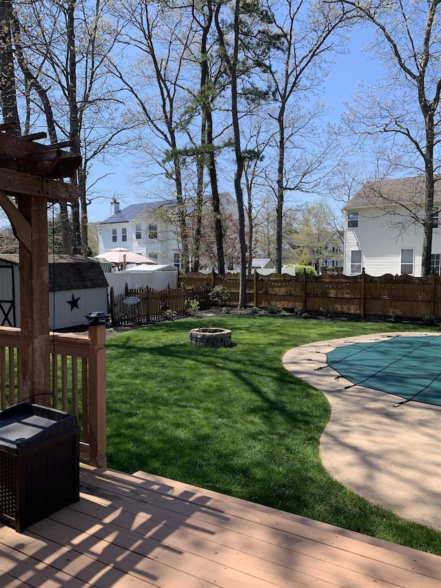 view of yard featuring a pool side deck, a pergola, a fire pit, and a shed