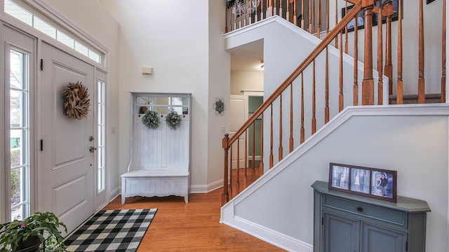 entryway with a healthy amount of sunlight, light hardwood / wood-style floors, and a high ceiling