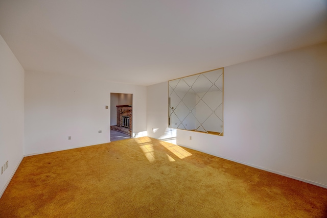 carpeted spare room with a brick fireplace