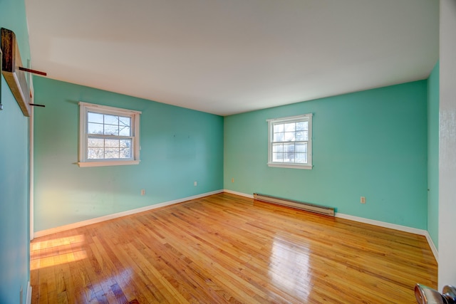 empty room with a baseboard radiator, plenty of natural light, and light hardwood / wood-style floors