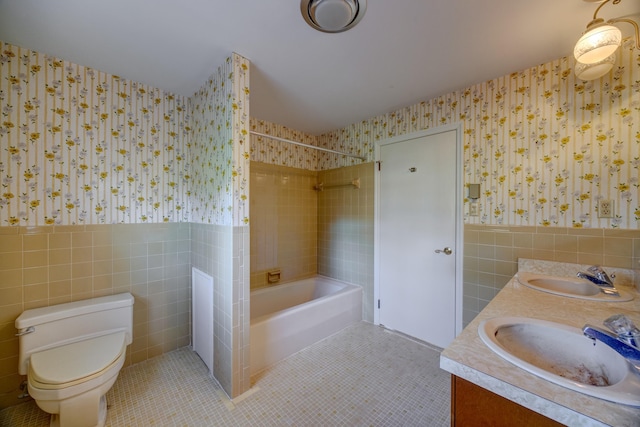 full bathroom with tiled shower / bath, tile walls, vanity, toilet, and tile patterned floors