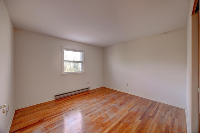 spare room featuring a baseboard radiator and light wood-type flooring