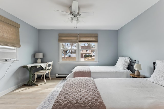 bedroom featuring a baseboard heating unit, wood finished floors, a ceiling fan, and baseboards