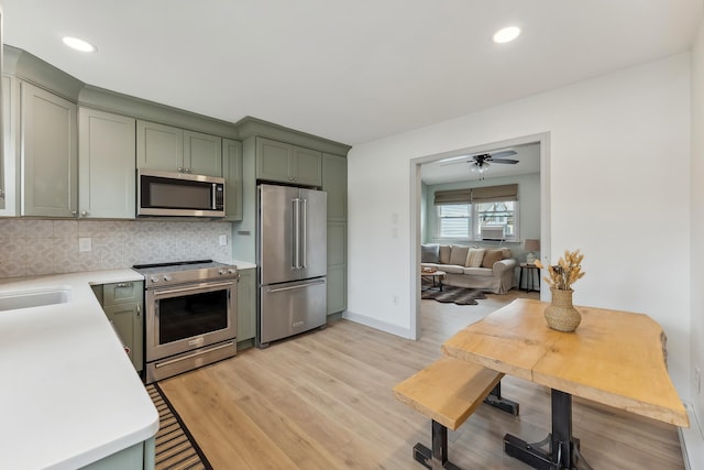 kitchen with light wood-style floors, tasteful backsplash, stainless steel appliances, and light countertops