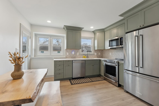 kitchen with a sink, light wood-style floors, green cabinetry, and premium appliances