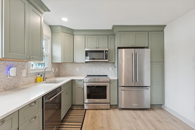 kitchen featuring appliances with stainless steel finishes, green cabinets, a sink, and light countertops