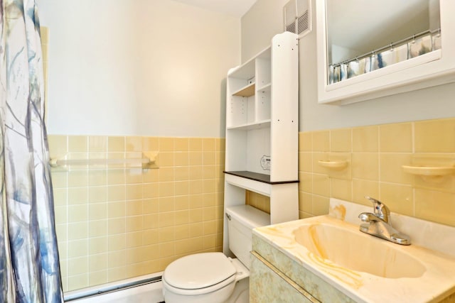full bathroom featuring tile walls, toilet, a wainscoted wall, visible vents, and baseboard heating