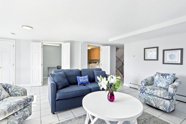 living area with stairway, light tile patterned floors, washing machine and dryer, and a baseboard radiator