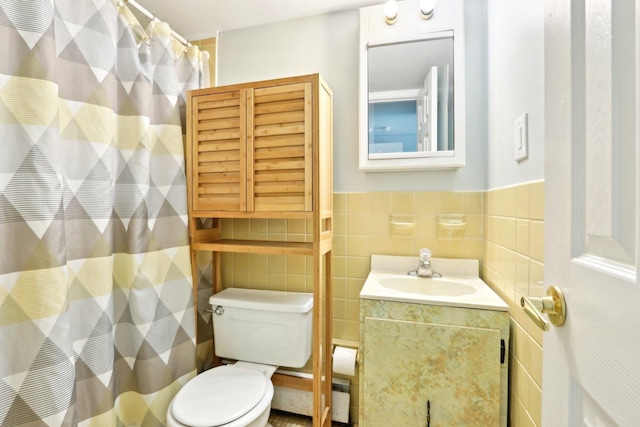 full bathroom featuring a shower with curtain, toilet, tile walls, vanity, and wainscoting