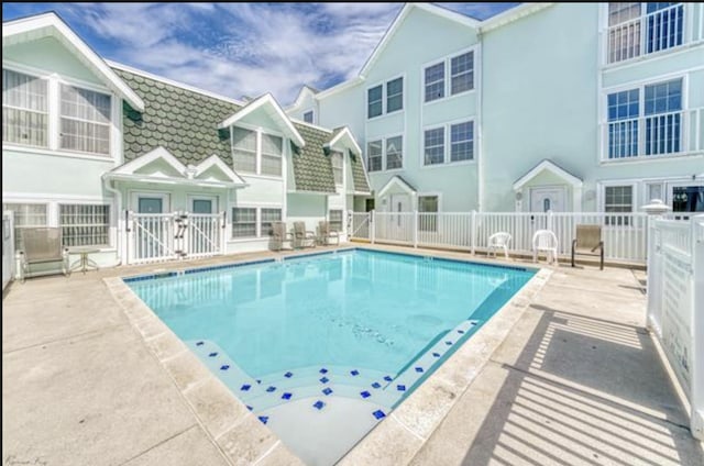 community pool with fence and a patio area