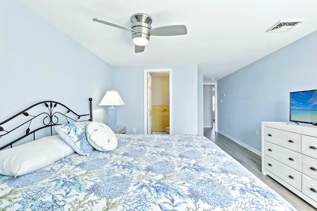 bedroom with wood finished floors, ensuite bath, baseboards, visible vents, and a ceiling fan