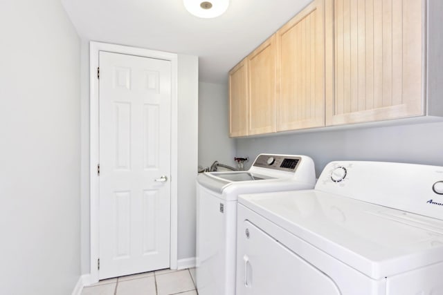 laundry room with light tile patterned floors, separate washer and dryer, cabinet space, and baseboards