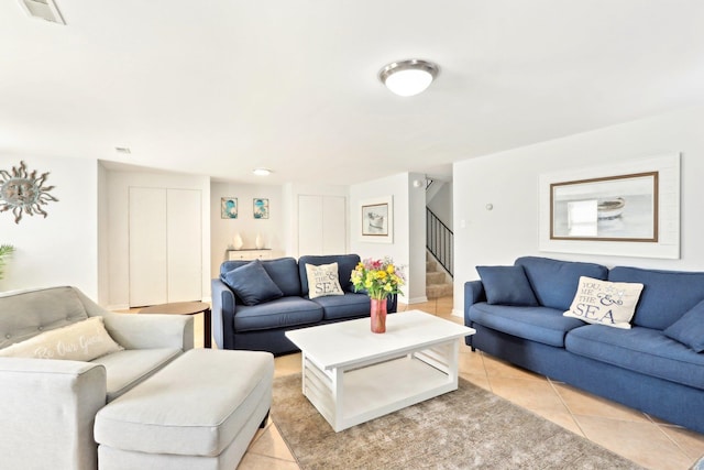 living room with light tile patterned flooring, visible vents, and stairway