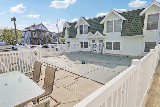 view of swimming pool featuring fence, a gate, a patio area, and a residential view