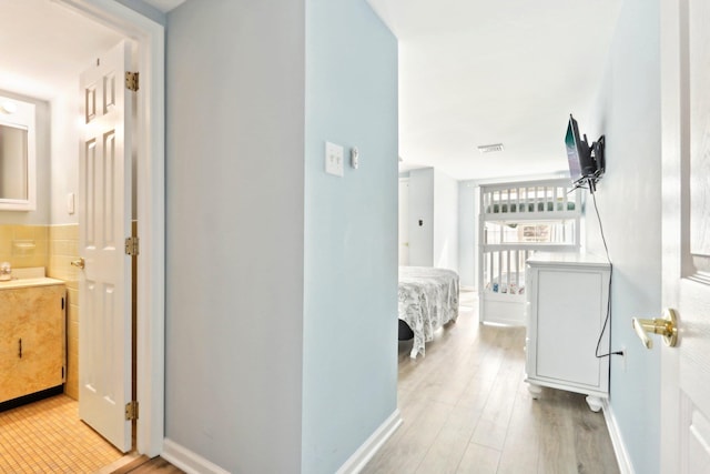 corridor with visible vents, light wood-type flooring, and baseboards