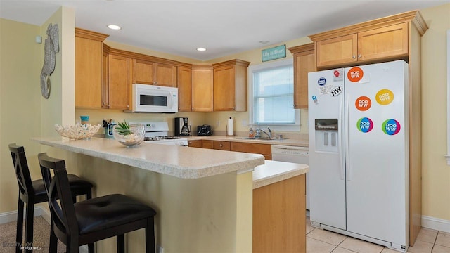 kitchen with a kitchen bar, light tile patterned floors, white appliances, and kitchen peninsula