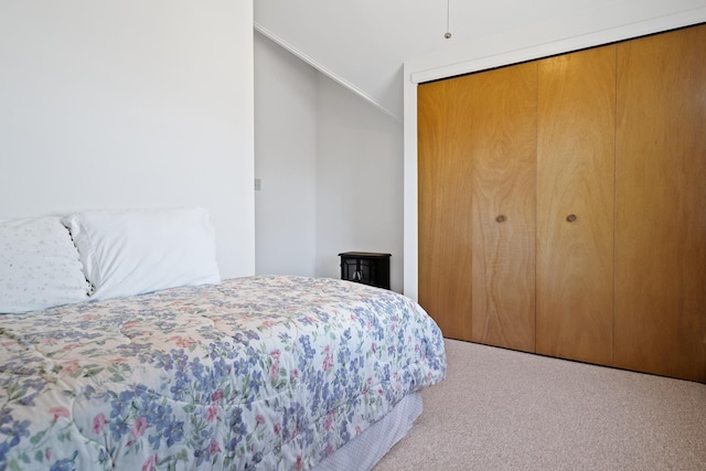 carpeted bedroom featuring vaulted ceiling and a closet