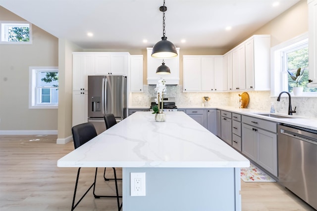 kitchen with appliances with stainless steel finishes, a center island, decorative light fixtures, and sink